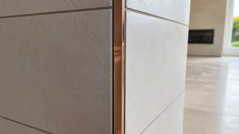 Profilé cuivre brillant posé sur un angle sortant entre deux surfaces carrelées