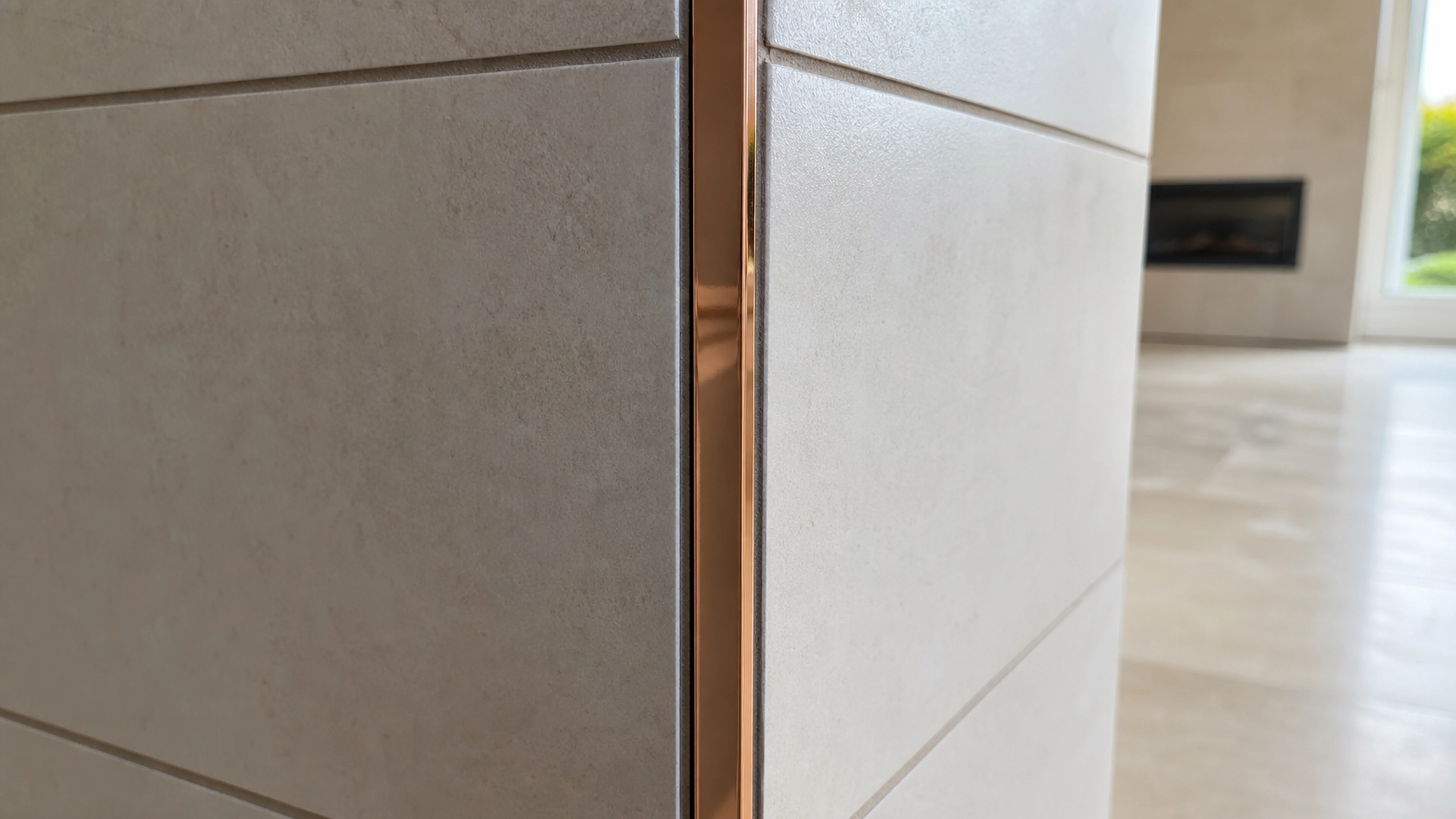 Profilé cuivre brillant posé sur un angle sortant entre deux surfaces carrelées